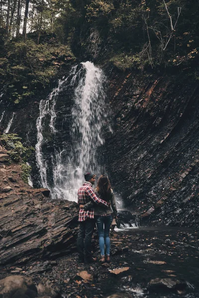 Verliebtes Paar umarmt sich in der Nähe des Wasserfalls — Stockfoto