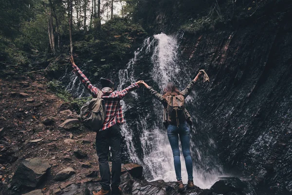 Casal apaixonado de pé perto de cachoeira — Fotografia de Stock