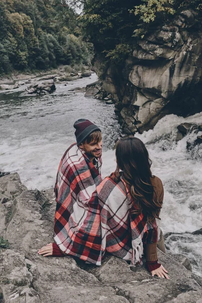 Paar bedekt met deken zittend op de rotsen — Stockfoto