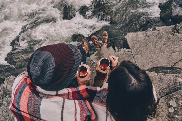 Paar bedekt met deken zittend op de rotsen — Stockfoto