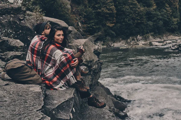 Casal coberto com cobertor sentado em rochas — Fotografia de Stock
