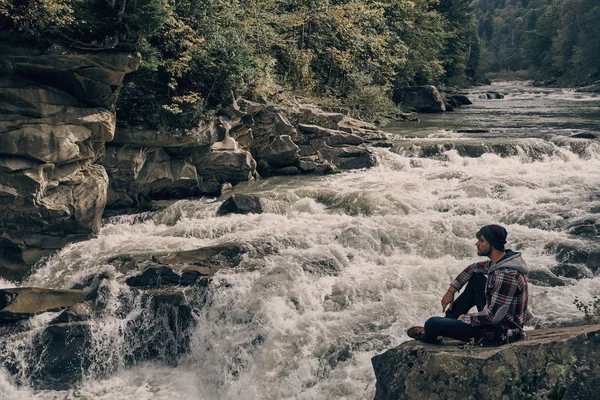 川の近くの岩の上に座って男 — ストック写真