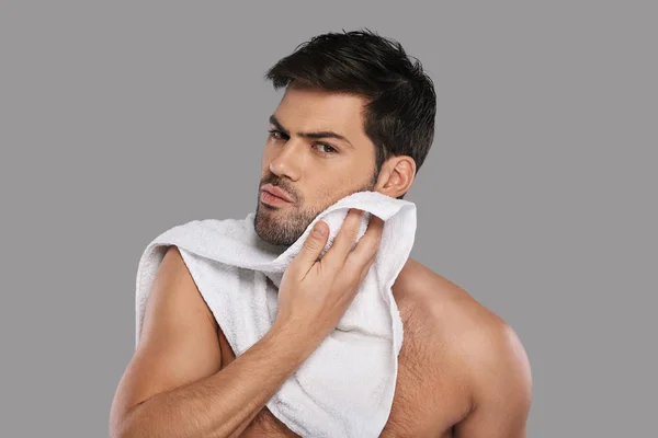 Bello Giovane Uomo Pulire Viso Con Asciugamano Contro Sfondo Grigio — Foto Stock