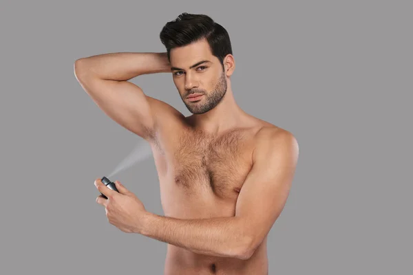 Shirtless Pohledný Mladý Muž Použití Deodorant Stoje Šedé Pozadí — Stock fotografie