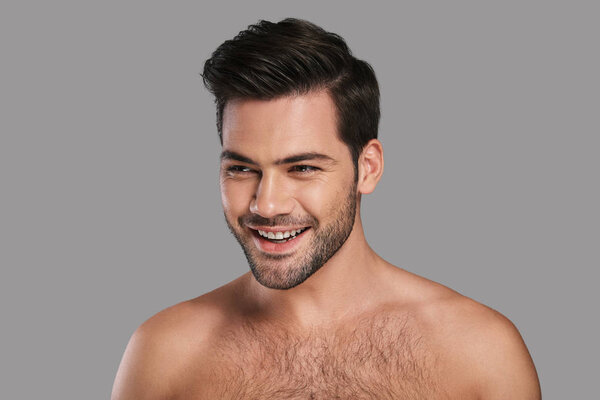 shirtless handsome young smiling man looking away against grey background