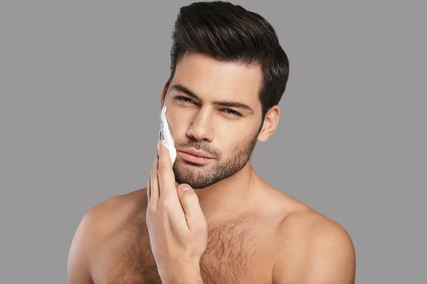 Handsome Young Man Applying Shaving Cream Looking Camera Grey Background — Stock Photo, Image
