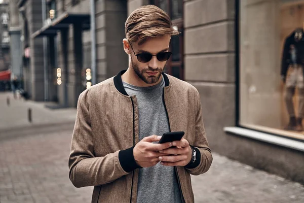 Yakışıklı Genç Adam Akıllı Telefonunu Kullanarak Rahat Kıyafet — Stok fotoğraf