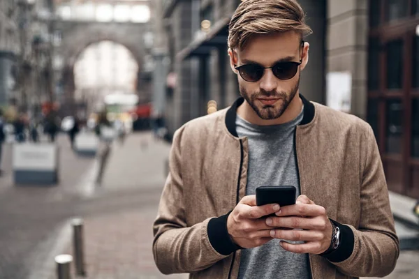 Yakışıklı genç adam rahat kıyafet smartphone arkadaşıyla Sohbet