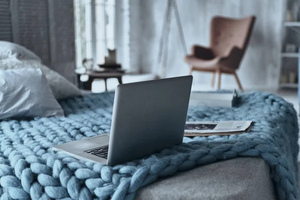 Close up of laptop and magazine on bed in nice cozy bedroom