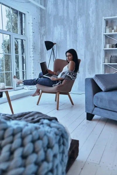 Evde Koltukta Otururken Dizüstü Bilgisayar Kullanan Çekici Blogger Kadın — Stok fotoğraf