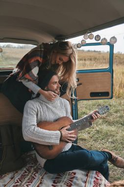 adam sarışın kız onu kucaklayan retro tarzı mini van arabada gitar ile 