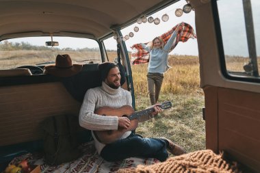 Battaniye ile alanında çalışan kadın ise akustik gitar çalmaya yakışıklı genç 