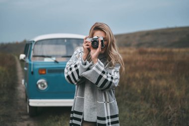Açık havada alanında ayakta iken dijital kamera kullanarak çekici sarışın fotoğrafçı kadın, 