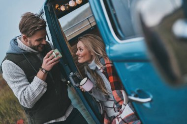 Sıcak içecekler ve onların yol tadını çıkarırken gülümseyen güzel genç Çift seyahat