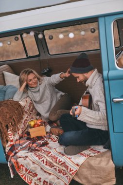 adam sevgilisini mavi retro tarzı mini van araba için akustik gitar yeni şarkı oynamak