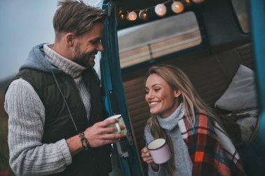 Sıcak içecekler ve onların yol tadını çıkarırken gülümseyen güzel genç Çift seyahat