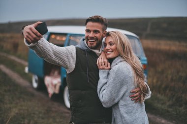 Selfie alma ve onların yol seyahat tadını çıkarırken gülümseyen güzel genç Çift