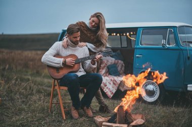 Yakışıklı genç gitar çalmak için çekici kız tarafından şenlik otururken adam