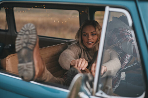 Attractive blonde woman adjusting shoes in mini van car 