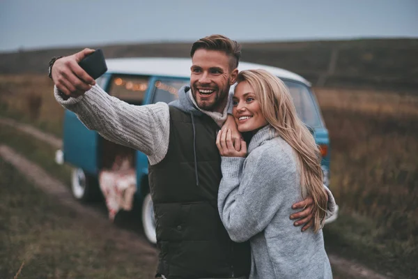 Selfie alma ve onların yol seyahat tadını çıkarırken gülümseyen güzel genç Çift