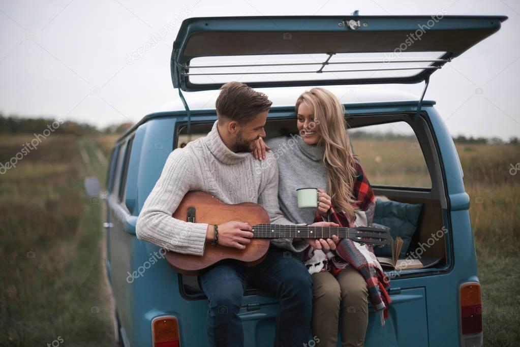 handsome man playing acoustic guitar for his beautiful blonde girlfriend