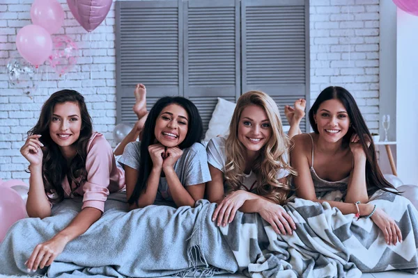 Четыре Привлекательные Молодые Женщины Пижаме Улыбаются Смотрят Камеру Лежа Кровати — стоковое фото
