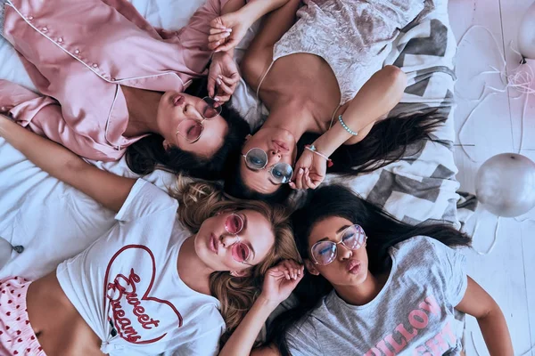 四美丽的年轻女性在床上躺在睡衣微笑的顶部视图 — 图库照片