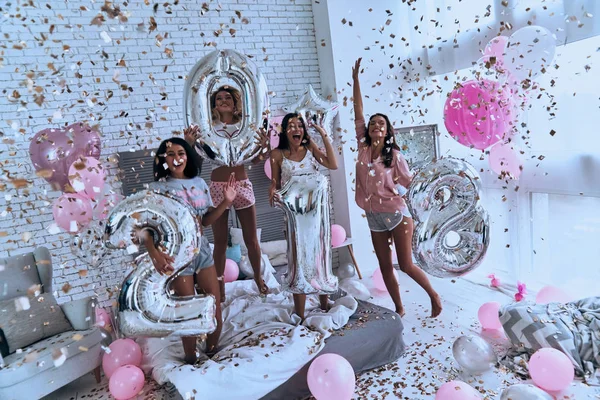 Attraktive Unge Kvinder Pyjamas Fejrer Nytår Soveværelset Med Flyvende Konfetti - Stock-foto