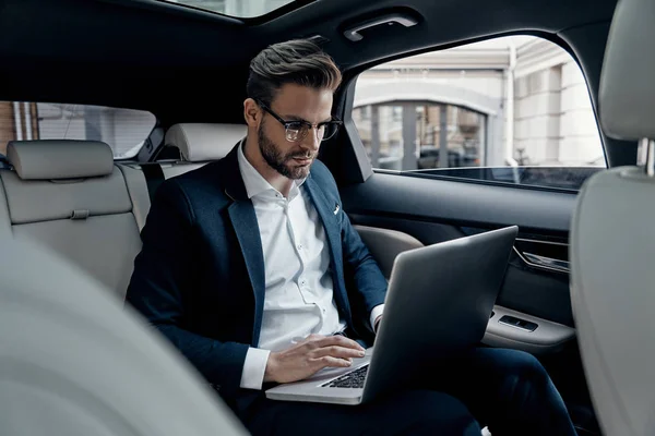 Självsäker Ung Man Kostym Använder Laptop Medan Sitter Bilen — Stockfoto