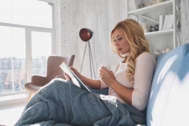 Çekici genç kadın evde kanepede otururken dijital tablet kullanma