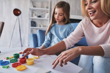 Parmakları ile anne ve kızı boyama ve evde zaman harcama gülümseyen