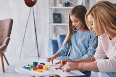 Parmakları ile anne ve kızı boyama ve evde zaman harcama gülümseyen