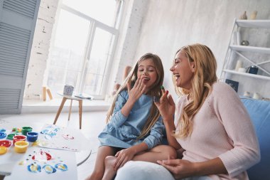 Sevimli küçük kız ve genç güzel kadın rahat evde gülüyor