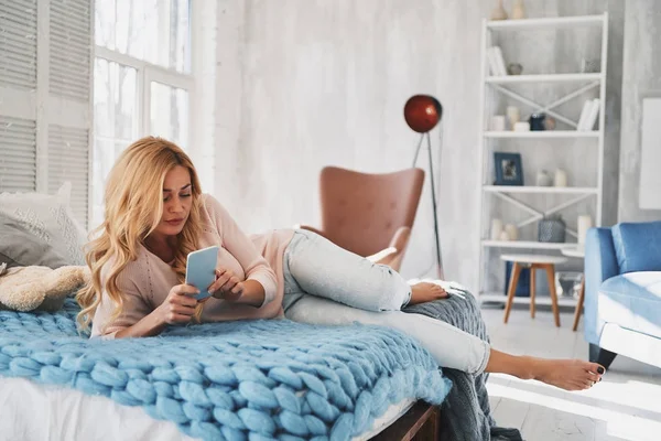 Aantrekkelijke Jonge Vrouw Slimme Telefoon Surfen Terwijl Liggend Bed Thuis — Stockfoto