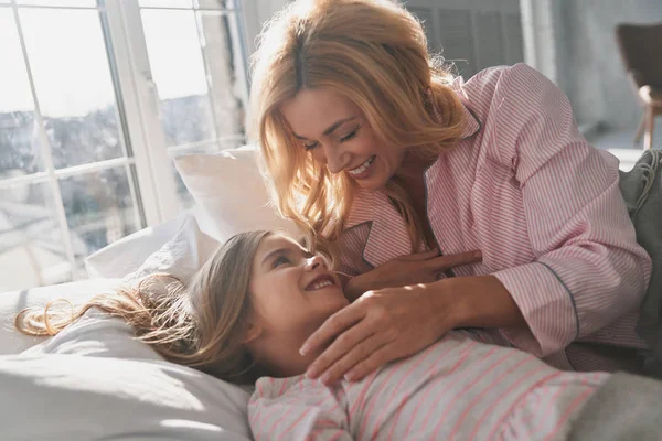 年轻美丽的母亲醒来 她可爱的小女儿和微笑 而躺在床上在家 — 图库照片
