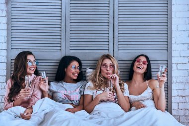 Kız kokteyl içme ve yatakta yatan gülümseyen pijama