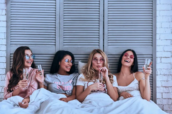Φίλες Τις Πυτζάμες Πίνοντας Κοκτέιλ Και Χαμογελαστός Ξαπλωμένοι Στο Κρεβάτι — Φωτογραφία Αρχείου