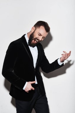 Yakışıklı genç takım gri arka plan karşı duran hayali gitar çalmak