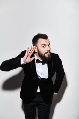 Tam takım kulağını gri arka plan karşı dururken yakınındaki el tutmak yakışıklı genç adam