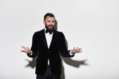 Memnun genç adam elleriyle işaret ve gri arka plan karşı duran bir surat elbiseli