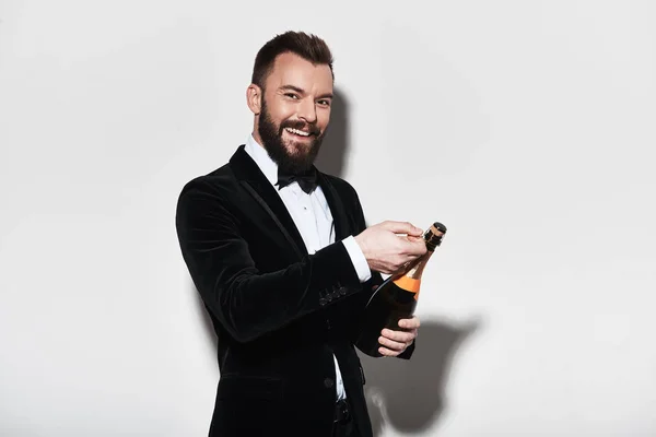 Pohledný Mladý Muž Obleku Otevření Láhev Šampaňského Usmívá Studiu — Stock fotografie