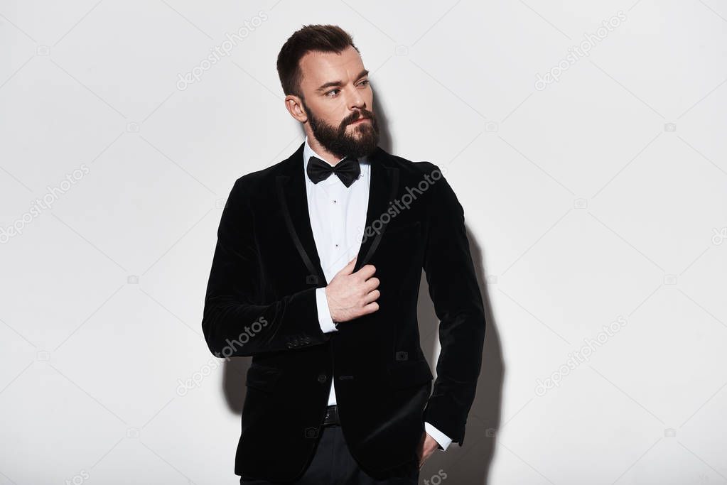 Portrait of confidence Handsome young man in suit adjusting his jacket in studio