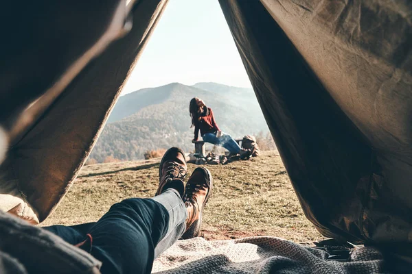 部分看法 接近的人欣赏山脉的看法和他的女朋友 而躺在帐篷 — 图库照片