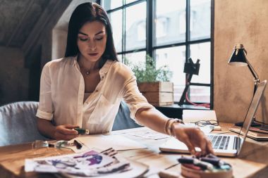 Onu atölye masasında otururken iplik tutan güzel genç kadın