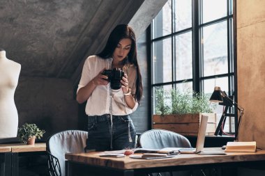 moda stilist kadın mezura atölyede dururken dijital kamera tutarak boyun ile