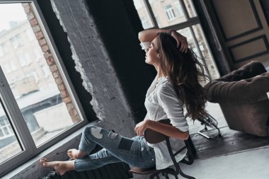 Sandalyede oturan ve saç dokunmadan rahat kıyafet içinde çekici esmer kadın
