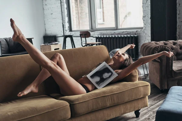 幸福的华丽的女人覆盖在沙发上躺在家里的杂志 — 图库照片