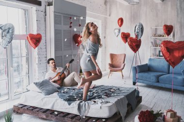 Süre evde Sevgililer günü kutlama güzel kız için gitar çalmak duygu oynak, genç adam