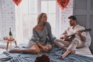 Süre evde Sevgililer günü kutlama güzel kız arkadaşı akustik gitar çalışını yakışıklı genç adam