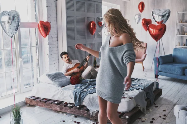 ハンサムな若い男の美しいガール フレンド 寝室で踊る女性のギターを弾く — ストック写真